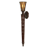 A Triomphe 1 Light Wall Torchiere featuring an elongated, intricate Firenze Gold metal base complemented by a warm-toned amber glass shade. Its decorative metalwork is reminiscent of a torch, exuding a vintage and elegant appearance.