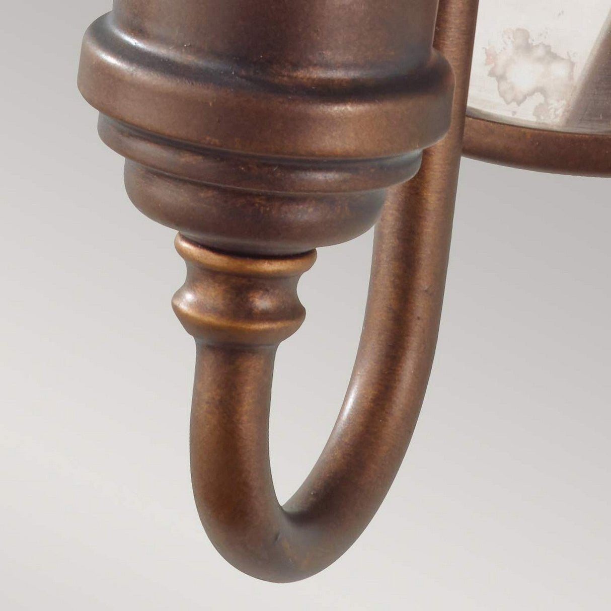 Close-up of a curved arm from the Urban Renewal 1 Light Wall Light in bronze, elegantly complemented by an Edison-style bulb. The metal features a smooth, polished finish with subtle hints of patina, highlighting its detailed craftsmanship against a soft, neutral background.