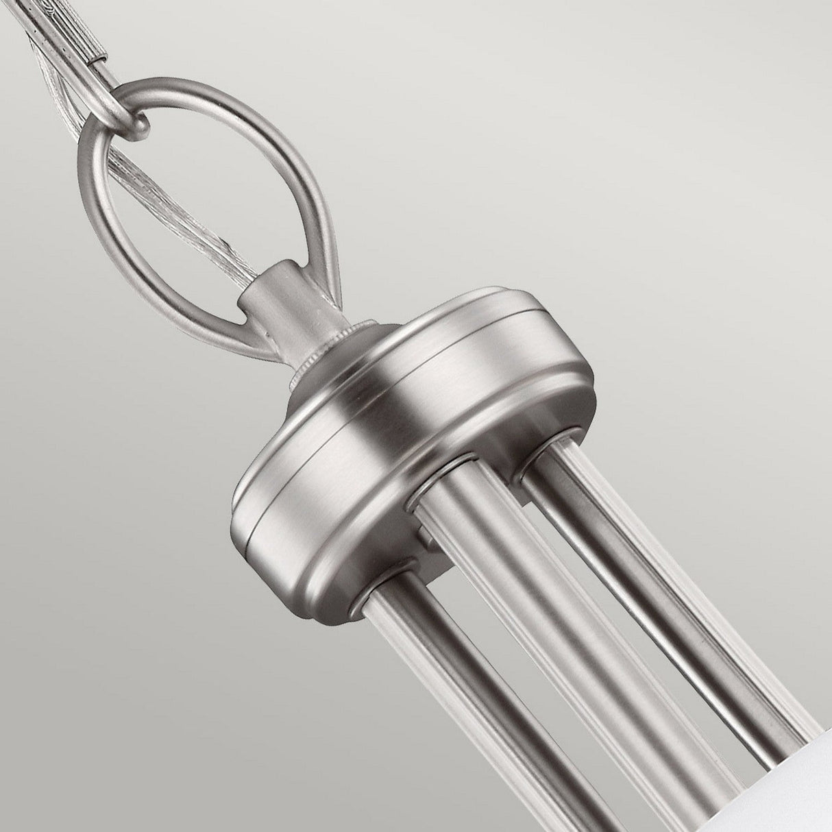 The Vintner 3 Light Chandelier in a satin nickel finish is showcased in a close-up view. This modern fixture includes three slender rods that support opal etched glass shades, with a sleek, circular canopy at the top. The background is a soft, neutral gray.