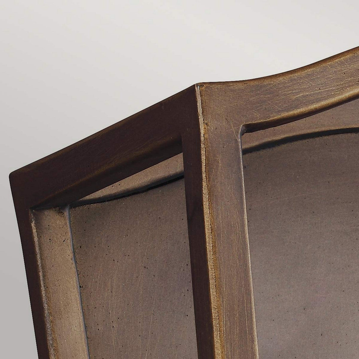 A close-up of a corner of a light, elegant frame with slightly curving edges, reminiscent of aged brass.