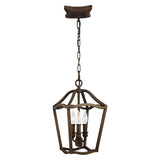 The Yarmouth 3 Light Chandelier in Painted Aged Brass features a vintage-style design with a geometric metal frame and three candle-like lights inside, all suspended by a chain from a square ceiling mount.