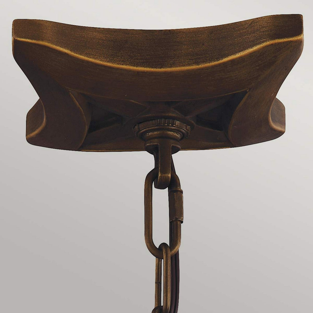A close-up of the Painted Aged Brass ceiling mount, adorned with a decorative chain, is set against a plain background. This design showcases curved edges and intricate craftsmanship akin to the elegant Yarmouth 4 Light Chandelier.