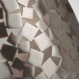 Close-up of a metallic surface with an abstract pattern of interlocking, triangular shapes in varying shades of silver and bronze, reminiscent of contemporary design. This textured, reflective appearance evokes the sleek elegance similar to the brushed steel elements found in the Zara 1 Light Wall Light - Brushed Steel.