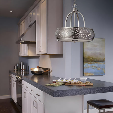 The modern kitchen features white cabinets, stainless steel appliances with a brushed steel finish, and a gray countertop. Above the counter with appetizers and a wok hangs the Zara 4 Light Chandelier in brushed steel. A landscape painting on the light blue wall enhances the contemporary design.