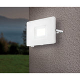 Fesvine LED Flood Light in white aluminium with recessed glass front, mounted on an outdoor wall bracket and illuminated against a textured render wall at dusk.