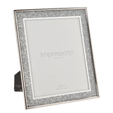Rectangular photo frame with silver glitter border and shiny silver rim, 8x10in aperture, shown with rear easel stand on a white background.