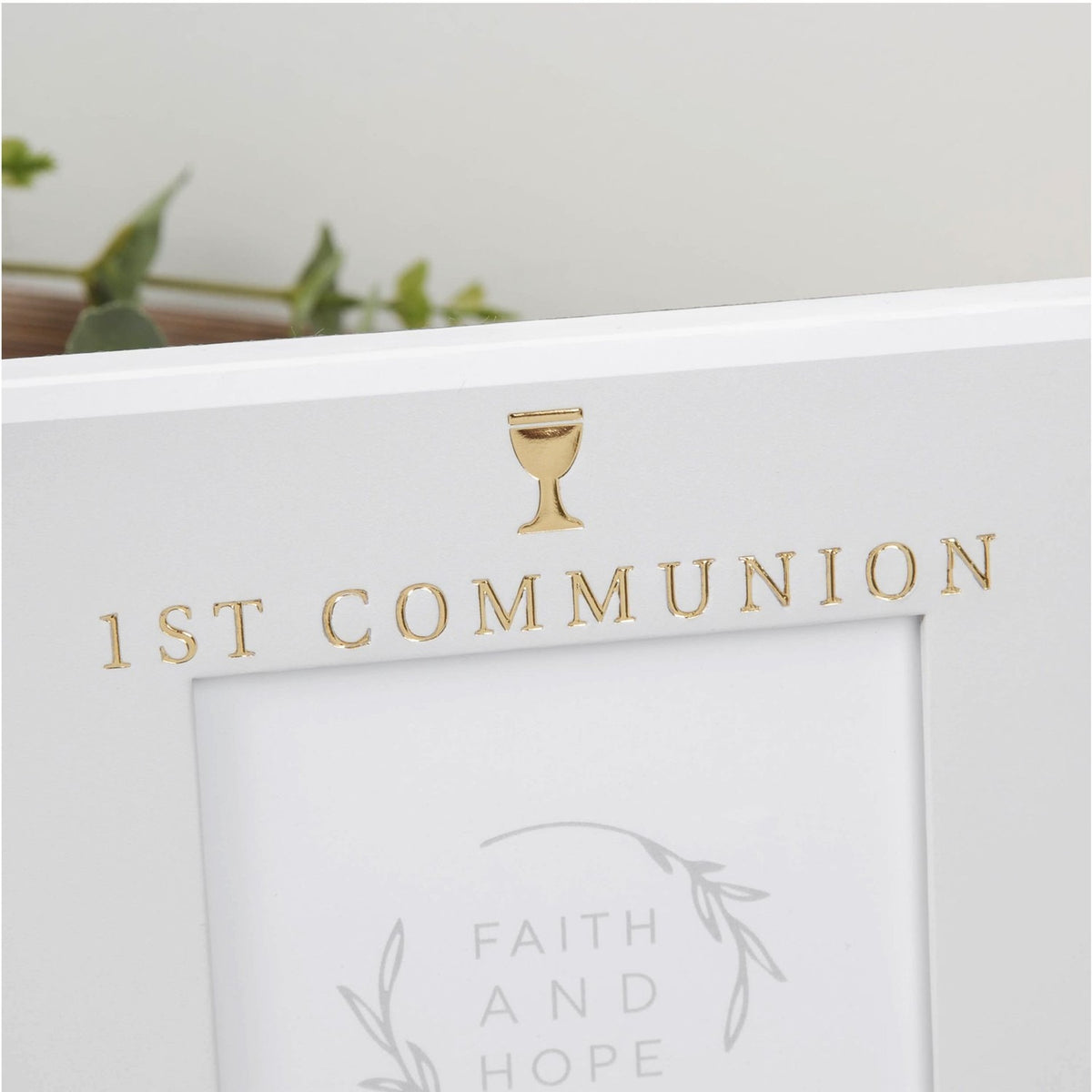 Close-up of the grey freestanding First Communion photo frame with white edges, gold "1ST COMMUNION" lettering and chalice icon above the rectangular 6 x 4in opening.