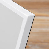 Close-up of the First Communion Freestanding Photo Frame 6 x 4in in grey, showing the white edge and corner detail with a blurred wood-tone background.