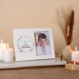 White rectangular photo frame with illustrated wreath, "Special Boy First Holy Communion" text, and a 6 x 4in photo slot, shown on a shelf with candles and dried grasses.