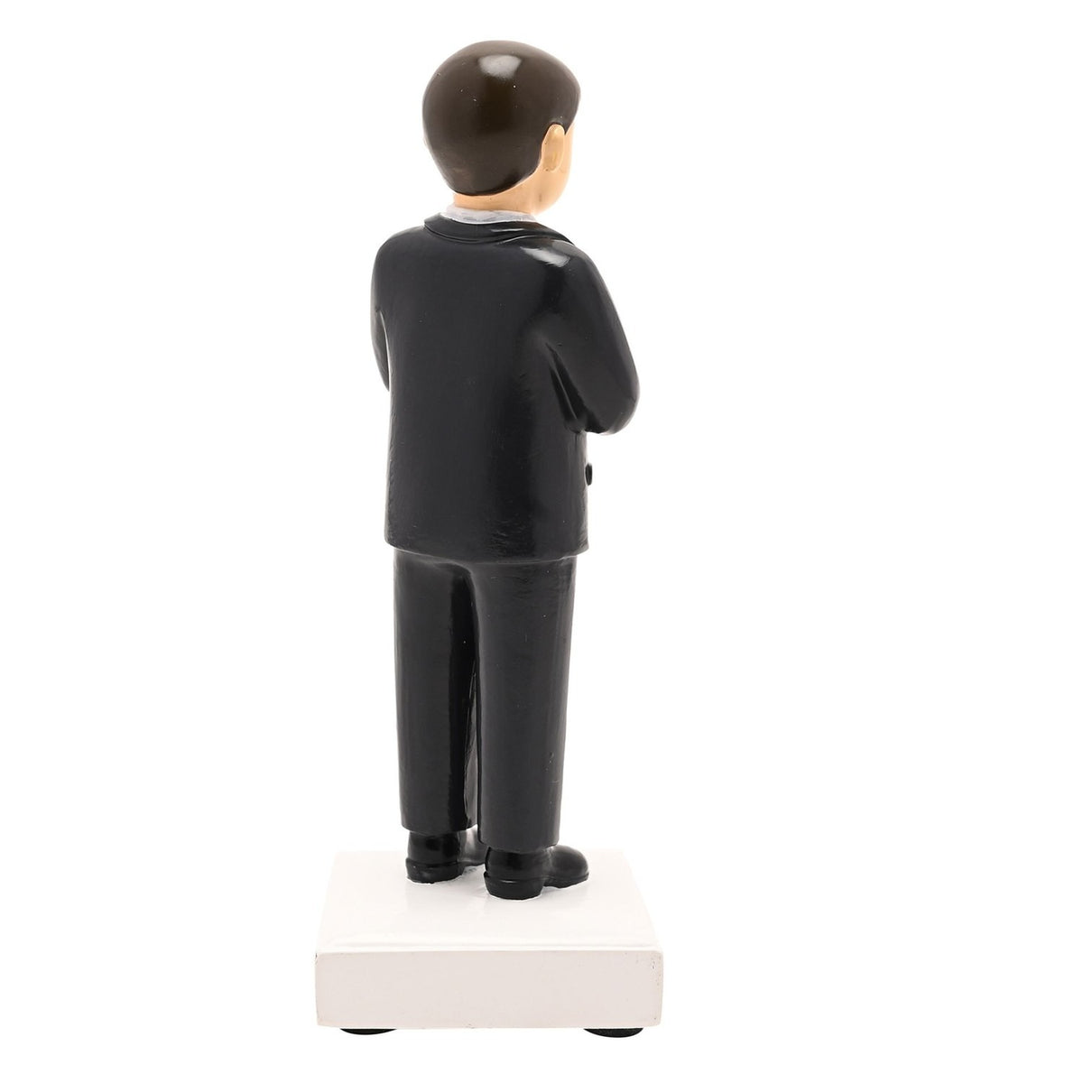 Rear view of the Communion Boy resin figurine in a black suit with neat brown hair, standing on a white square base against a plain background.