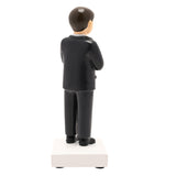 Rear view of the Communion Boy resin figurine in a black suit with neat brown hair, standing on a white square base against a plain background.