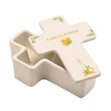 White ceramic cross-shaped trinket box with lid ajar, lid printed "CHRISTENING" in gold with a heart, candle, and leaf motifs, set against a plain white background.