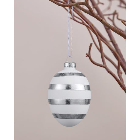 Fintry Glass Decorative Egg in matt white with four brushed silver stripes, hanging by a silver cord with a silver cap, shown against twigs and a neutral background.