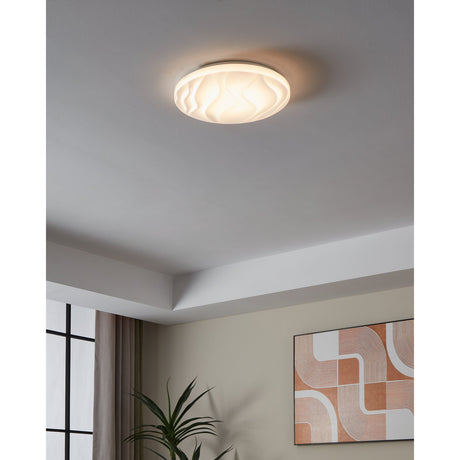 Fismenne LED flush ceiling light, 33cm round white plastic diffuser with wave texture and white steel body, shown lit on a bedroom ceiling.