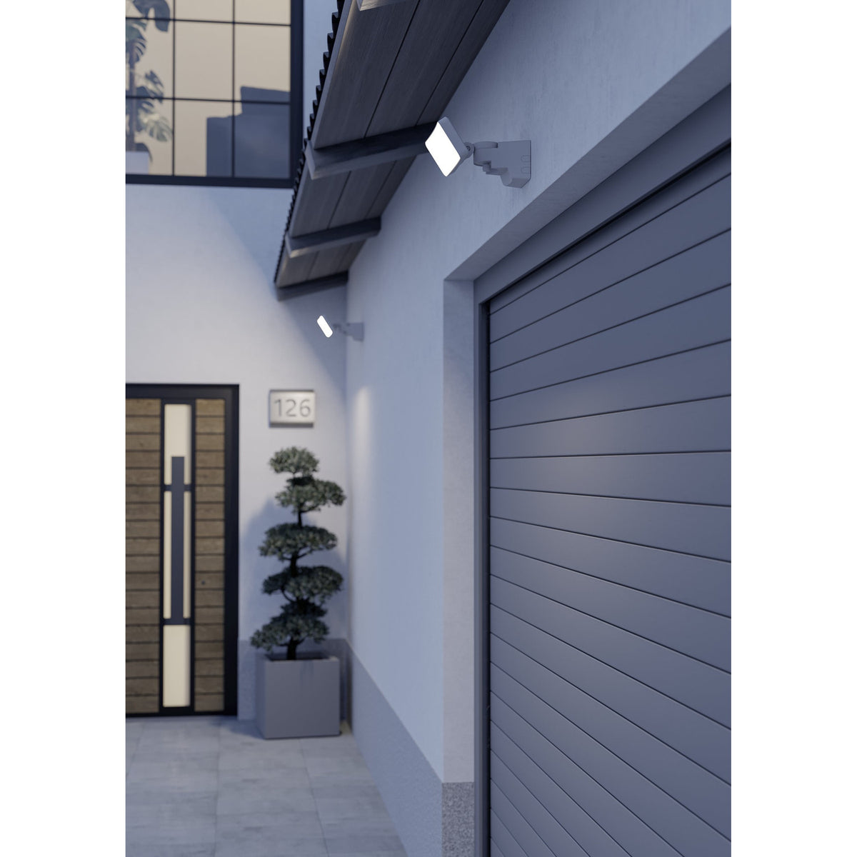 Epifano LED Flood Light 100W in white, wall-mounted with rectangular head on adjustable bracket, shown illuminating a modern house exterior near a garage door at dusk.