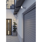 Epifano LED Flood Light 100W in White, wall-mounted with adjustable bracket above a garage door, illuminating an outdoor entryway at dusk.