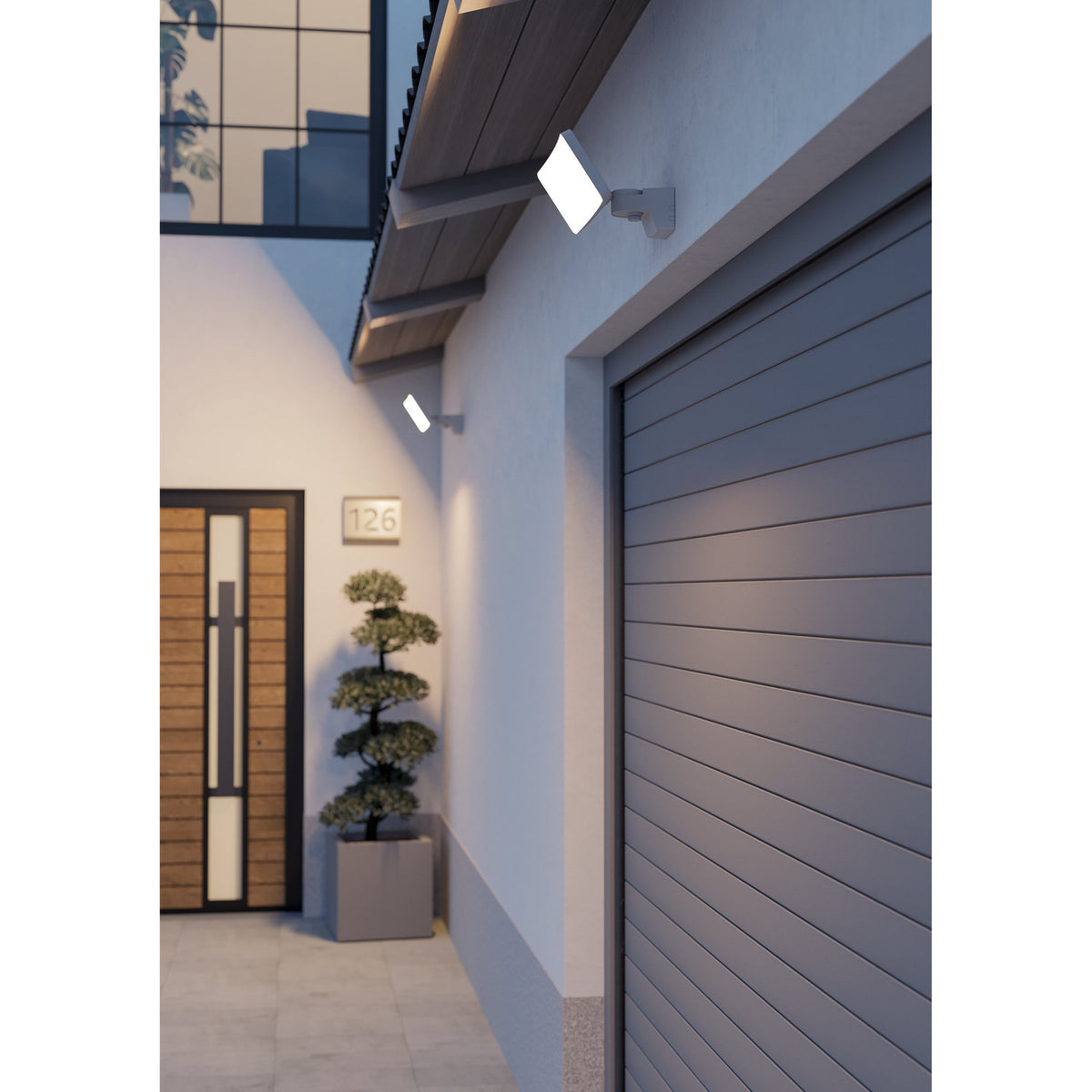 Epifano LED Flood Light 180W in white, wall-mounted with adjustable bracket above a garage door and entrance, illuminating the exterior of a modern house at dusk.