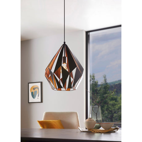 Flermanne Pendant Light 38.5cm in black and copper, faceted steel shade with angular cut-outs, shown on a black cord above a dining table in a living space.