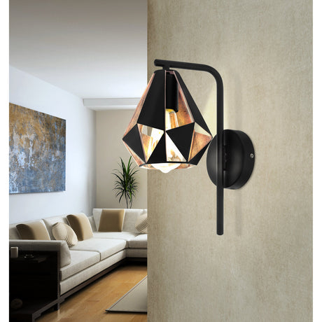 Flermanne wall light in a living room, featuring a black curved arm and round wall plate with a faceted steel shade in black and antique copper, E27 bulb visible.