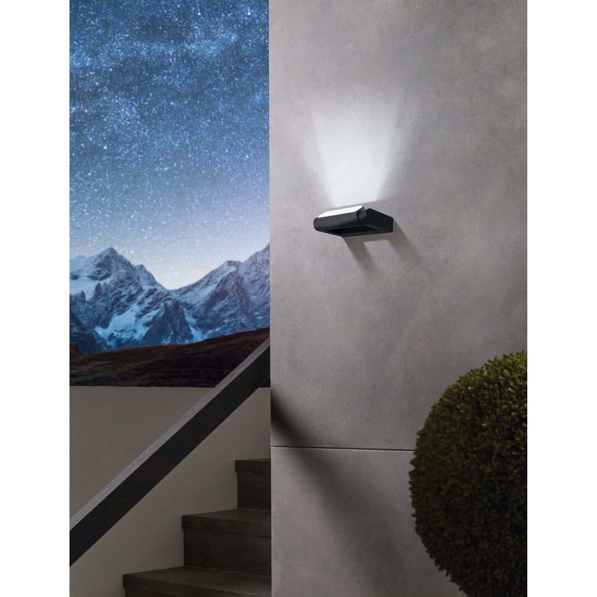Flirmane LED Outdoor Wall Light in black aluminium, slim rectangular frame with cylindrical head, mounted on an exterior grey wall casting an upward light beam.