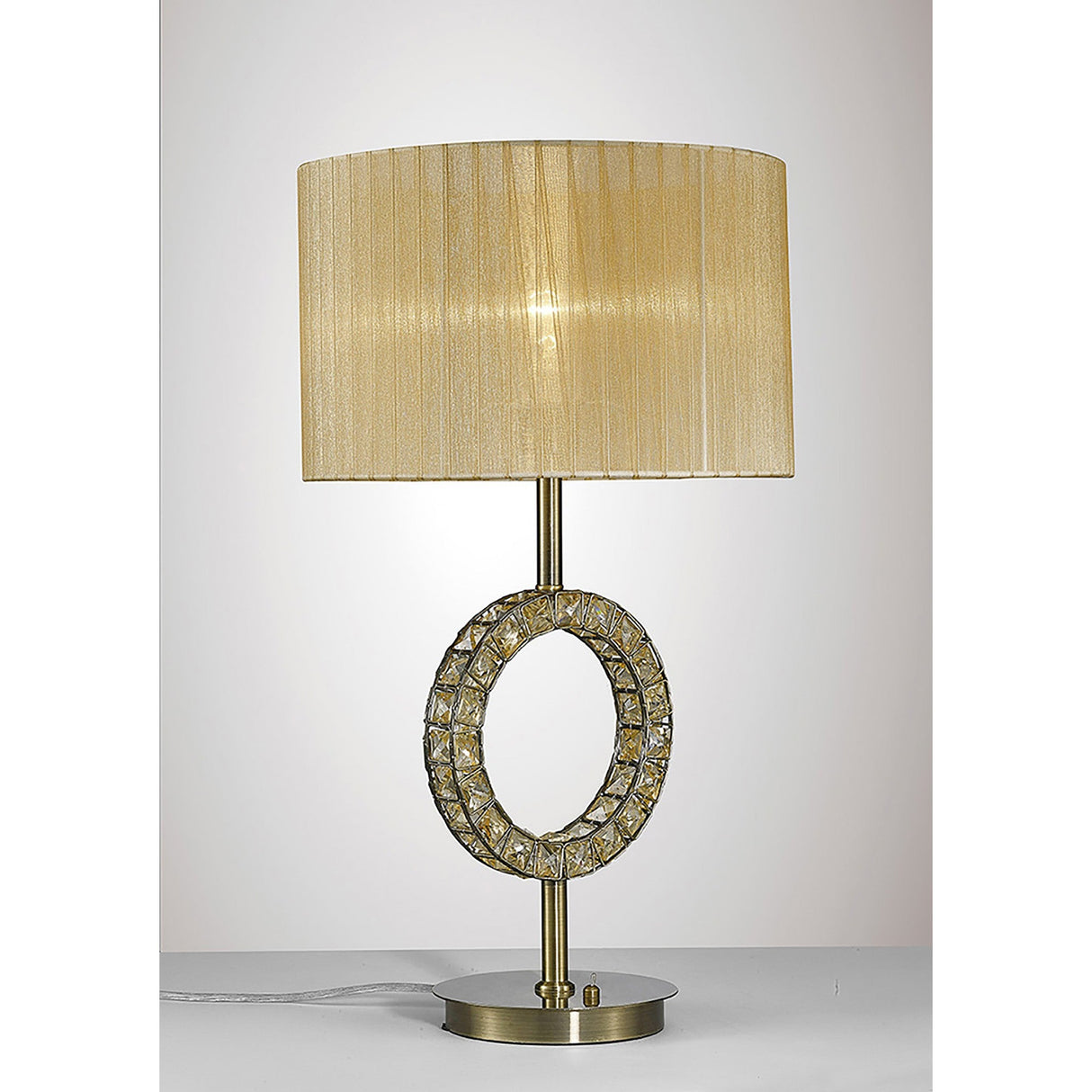 The Florence Round 1 Light Crystal Table Lamp features a brass cylindrical base, crystal-accented circular ring, and a soft bronze pleated shade, displayed on a white surface against a light backdrop.