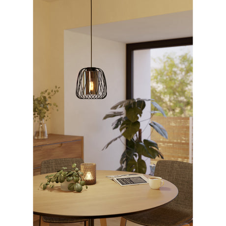 Floresta Smoked Glass Pendant Light in black, its woven steel wire cage and smoked glass shade hanging above a round wooden dining table.