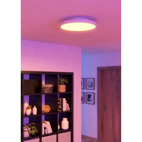 Flornorne 45cm round LED flush ceiling light in white, glowing warm against a pink-lit hallway ceiling near an open-shelf unit and framed wall art.