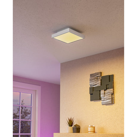 Flornorne square LED ceiling panel light in white, 30 x 30cm, mounted flush on a textured ceiling and glowing warm white above a pink and neutral-toned room.