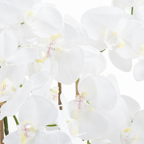 Close-up of Hill Interiors Large White Tall Orchid faux plant showing waxy white petals with yellow centres and red speckled throats on arching stems.