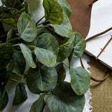 Hill Interiors Short Eucalyptus Bunch with rounded silvery-green plastic leaves, styled on white linen beside a leather-bound journal.