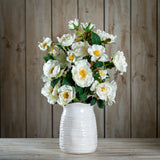 Hill Interiors White Tea Rose faux stems arranged in a textured white ceramic vase against a wooden plank backdrop.