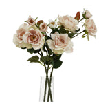Hill Interiors Palest Blush Tea Rose faux stems with soft pink layered blooms, buds and green foliage arranged in a clear glass vase on a white background.