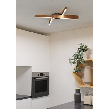 Folcino Smart Colour Changing LED Flush Ceiling Light with bronze crossed arms and black round base, mounted on a white kitchen ceiling above cabinetry and a wall oven.
