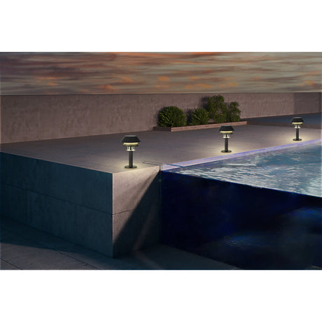 Fornena black and white outdoor post lights with stacked conical shades line a poolside patio at dusk, casting warm light near the water's edge.