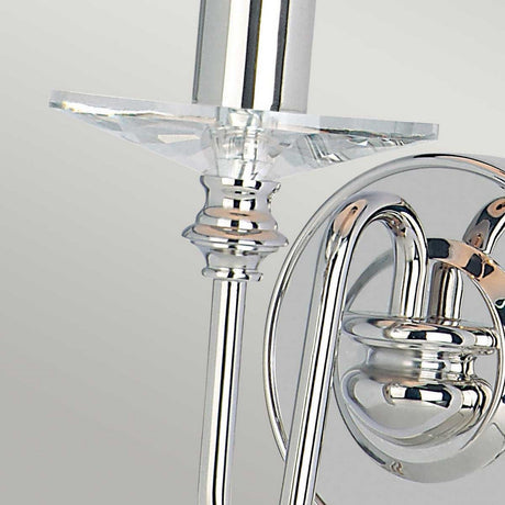 A close-up of the Finsbury Park 1 Light Wall Light - Polished Nickel, highlighting a contemporary wall sconce with a chrome finish and an elegant, curved design. The fixture boasts a polished nickel cylindrical base adorned with clear, circular hand-cut glass droplets that gently reflect light on its shiny surface.