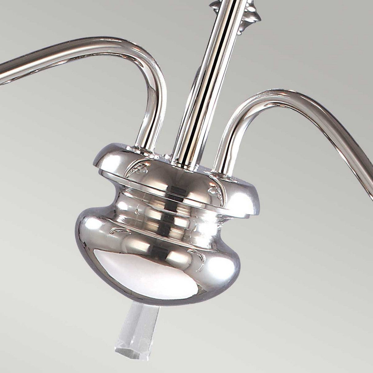 Close-up of the Finsbury Park 3 Light Chandelier in polished nickel, featuring gracefully curved arms and a central stem, set against a light gray background. The metal surface shines brilliantly, beautifully reflecting the light.