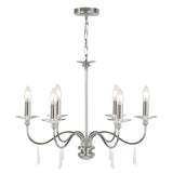 The Finsbury Park 6 Light Chandelier - Polished Nickel is a sleek, modern fixture crafted with a polished nickel finish and six candle-style light bulbs. It boasts elegantly curved arms adorned with hand-cut glass accents, all gracefully suspended from a chain.
