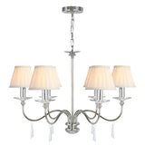The Finsbury Park 6 Light Chandelier features a contemporary Polished Nickel finish with six gracefully curved arms, each accented by a white lampshade and sparkling crystal details. It hangs elegantly from a chain, showcasing hand-cut glass embellishments that complement its modern style.