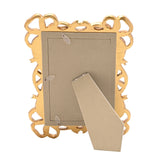 Back view of the Bowknot Design gold resin photo frame, showing a beige cardboard backing with a fold-out easel stand, set against a plain white background.