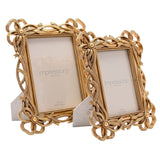 Two gold resin photo frames with bowknot corner details and openwork ribbon borders, 5x7 and 4x6 sizes, shown with easel backs on a white background.