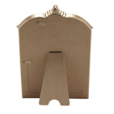 Back view of the Winged Arch Resin Photo Frame in champagne, showing the kraft-brown cardboard backing, hinged clasp, and fold-out easel stand against a white background.