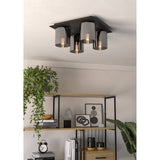 Fralvessa 4 Light Ceiling Light in black, square steel plate with four cylindrical smoky glass shades, shown mounted on a living room ceiling above open shelving.