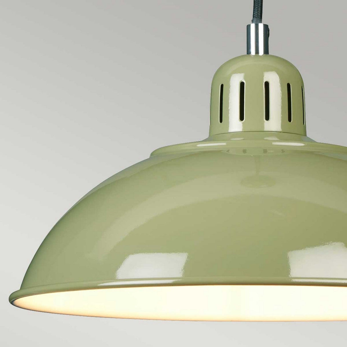 A close-up of the Franklin Pendant Light - Green showcases its retro-inspired charm with a light green, glossy finish. The lamp is illuminated, providing a warm glow that serves as ideal task lighting against a neutral gray background.