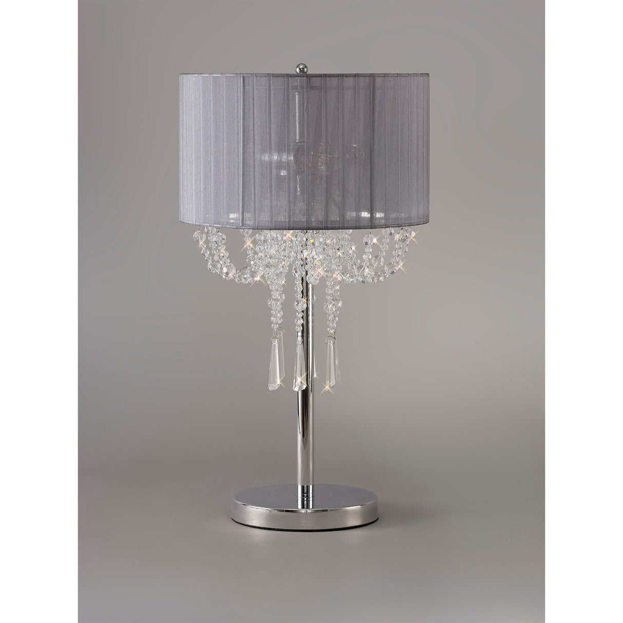 The Freida 3 Light Crystal Table Lamp features a polished chrome base, a grey shade, and decorative hanging crystals, set against a plain gray background.