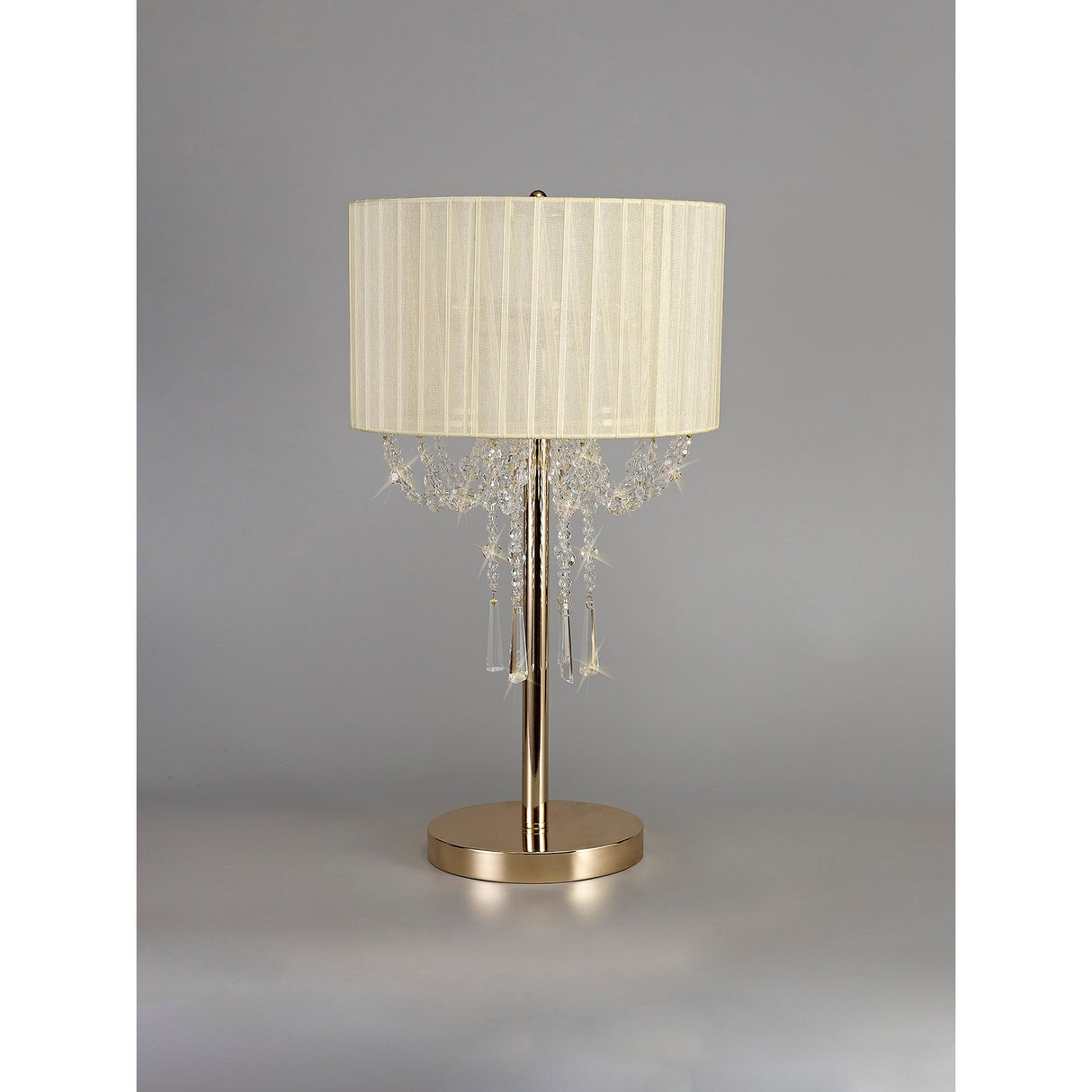 The Freida 3 Light Crystal Table Lamp features a French Gold base, stem, and luxurious ivory cream shade with crystal-like accents, offering elegant lighting on a plain gray background.