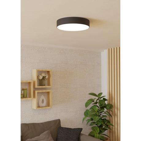 Frelvine Smart LED Flush Ceiling Light 39cm in black, round drum with white diffuser, shown mounted on a living room ceiling above a wood-shelved wall and sofa.