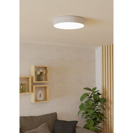 Frelvine Smart LED Flush Ceiling Light 39cm in white, a round low-profile drum fixture glowing softly on a living room ceiling above wooden shelving and a leafy plant.