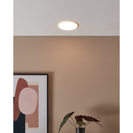 Fremora LED Downlight 15.5cm in White, round recessed ceiling fixture with warm white glow, shown installed in a room with tan walls and decorative artwork.