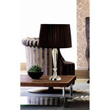 The Freya 1 Light Crystal Table Lamp - Silver Without Shade sits on a wooden coffee table near a small potted plant, with a striped armchair and floral wallpaper in the background.