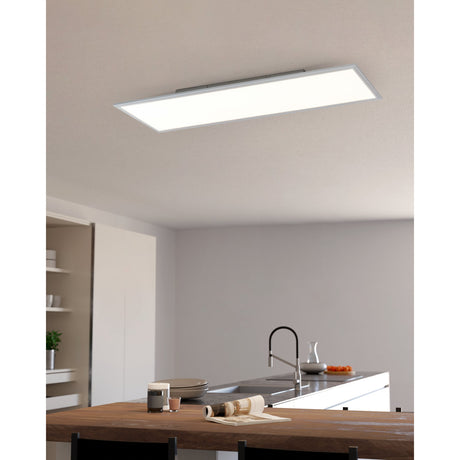 Frinarne rectangular LED ceiling panel light, 120 x 30cm, with white aluminium frame and glowing white diffuser, shown illuminated above a kitchen island.